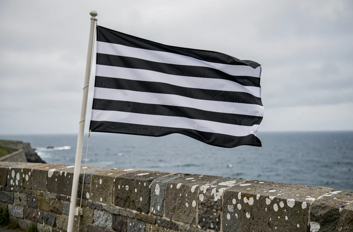 Drapeau breton flottant sur une fortification côtière en granit avec vue sur l'Atlantique en arrière-plan